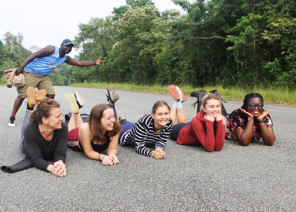 The Forest’s Green Embargo
By 8:30 AM, our caravan surged forward, breaching the emerald fortifications of Kibale National Park. We paused within the cathedral of the green canopy for a mandatory "aesthetic intervention," a moment where the modern human’s obsession with pixels met the ancient world's indifference. As shutters clicked and poses were struck against the backdrop of thousand-year-old mahogany trees, we found ourselves under the judgmental surveillance of the local primate aristocracy. The monkeys, swinging with a nonchalance that bordered on the theatrical, engaged in a cacophony of arboreal gossip, likely debating whether our flamboyant trekking gear was the latest in "Great Ape" couture or merely a tragic evolutionary detour. We were merely transients in their leafy kingdom, yet for a moment, the boundary between human and wild dissolved in the humidity of the rainforest, leaving us humbled by the sheer density of life pulsating in every leaf and shadow.